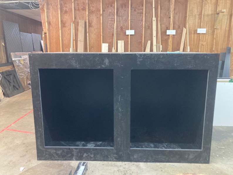 May include: A black wooden cabinet with two open compartments. The cabinet has a rough, textured surface.