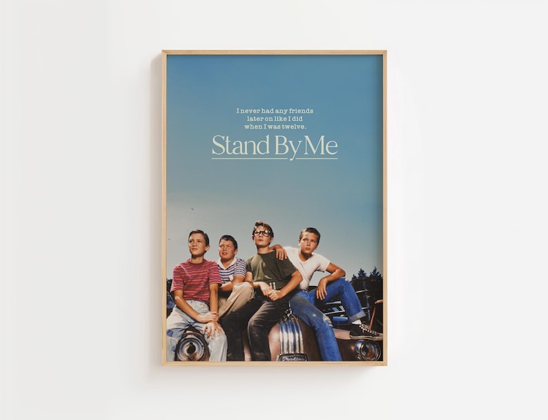 May include: A framed poster featuring four young boys sitting on a car. The poster has a blue sky background with the text "I never had any friends later on like I did when I was twelve. Stand By Me."