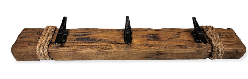 Solid wood nautical theme style look wall mounted coat or towel rack for the bathroom or entryway. This coastal themed towel hooh has rust proof black cast iron boat dock cleats or deck hooks. the wood is distressed and aged with the look of driftwood or reclaimed wood.