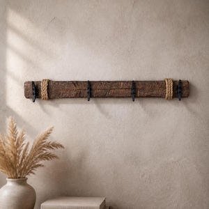 Solid wood nautical theme style look wall mounted coat or towel rack for the bathroom or entryway. This coastal themed towel hooh has rust proof black cast iron boat dock cleats or deck hooks. the wood is distressed and aged with the look of driftwood or reclaimed wood.