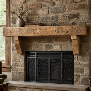 Peut inclure: Une poutre de cheminée en bois rustique à la texture vieillie, soutenue par deux consoles en bois assorties. Le manteau est monté au-dessus d'un écran de cheminée en métal noir avec un motif en losange, sur un mur en pierre texturée.