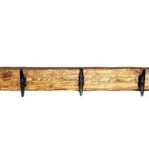 Solid wood nautical theme style look wall mounted coat or towel rack for the bathroom or entryway. This coastal themed towel hooh has rust proof black cast iron boat dock cleats or deck hooks. the wood is distressed and aged with the look of driftwood or reclaimed wood.