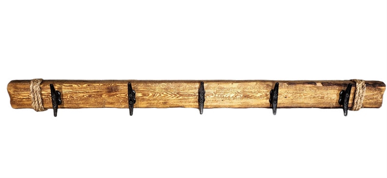 Solid wood nautical theme style look wall mounted coat or towel rack for the bathroom or entryway. This coastal themed towel hooh has rust proof black cast iron boat dock cleats or deck hooks. the wood is distressed and aged with the look of driftwood or reclaimed wood.