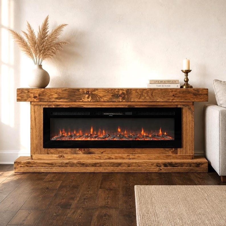 May include: A rectangular electric fireplace console constructed from dark stained wood with a prominent grain pattern. The unit features a wide, black glass-fronted firebox displaying a glowing orange flame effect and artificial logs.