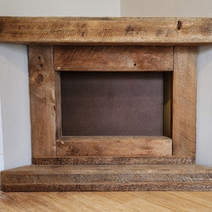 Pu&ograve; includere: Un camino rustico in legno con un'apertura rettangolare e uno scaffale inferiore. Il camino &egrave; realizzato in legno riciclato con una finitura naturale.