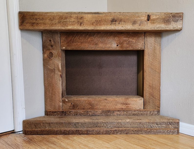 Pu&ograve; includere: Un camino rustico in legno con un'apertura rettangolare e uno scaffale inferiore. Il camino &egrave; realizzato in legno riciclato con una finitura naturale.