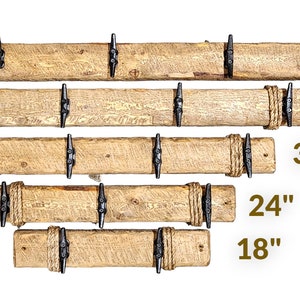 Solid wood nautical theme style look wall mounted coat or towel rack for the bathroom or entryway. This coastal themed towel hooh has rust proof black cast iron boat dock cleats or deck hooks. the wood is distressed and aged with the look of driftwood or reclaimed wood.