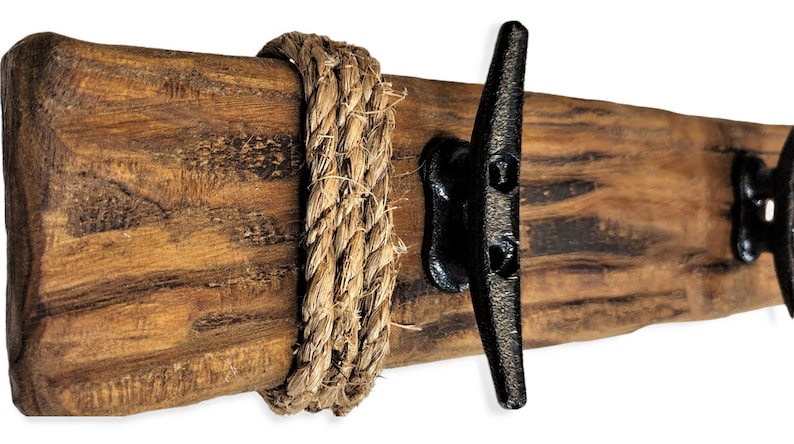 Solid wood nautical theme style look wall mounted coat or towel rack for the bathroom or entryway. This coastal themed towel hooh has rust proof black cast iron boat dock cleats or deck hooks. the wood is distressed and aged with the look of driftwood or reclaimed wood.