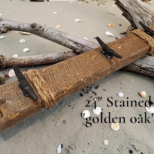 Solid wood nautical theme style look wall mounted coat or towel rack for the bathroom or entryway. This coastal themed towel hooh has rust proof black cast iron boat dock cleats or deck hooks. the wood is distressed and aged with the look of driftwood or reclaimed wood.