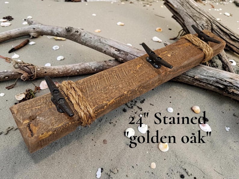 Solid wood nautical theme style look wall mounted coat or towel rack for the bathroom or entryway. This coastal themed towel hooh has rust proof black cast iron boat dock cleats or deck hooks. the wood is distressed and aged with the look of driftwood or reclaimed wood.