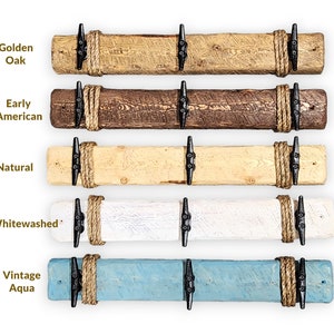 Solid wood nautical theme style look wall mounted coat or towel rack for the bathroom or entryway. This coastal themed towel hooh has rust proof black cast iron boat dock cleats or deck hooks. the wood is distressed and aged with the look of driftwood or reclaimed wood.