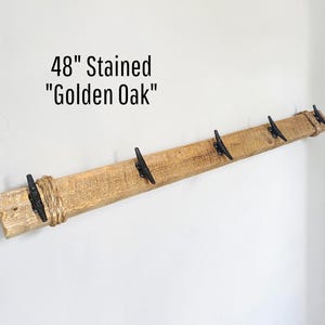 Solid wood nautical theme style look wall mounted coat or towel rack for the bathroom or entryway. This coastal themed towel hooh has rust proof black cast iron boat dock cleats or deck hooks. the wood is distressed and aged with the look of driftwood or reclaimed wood.