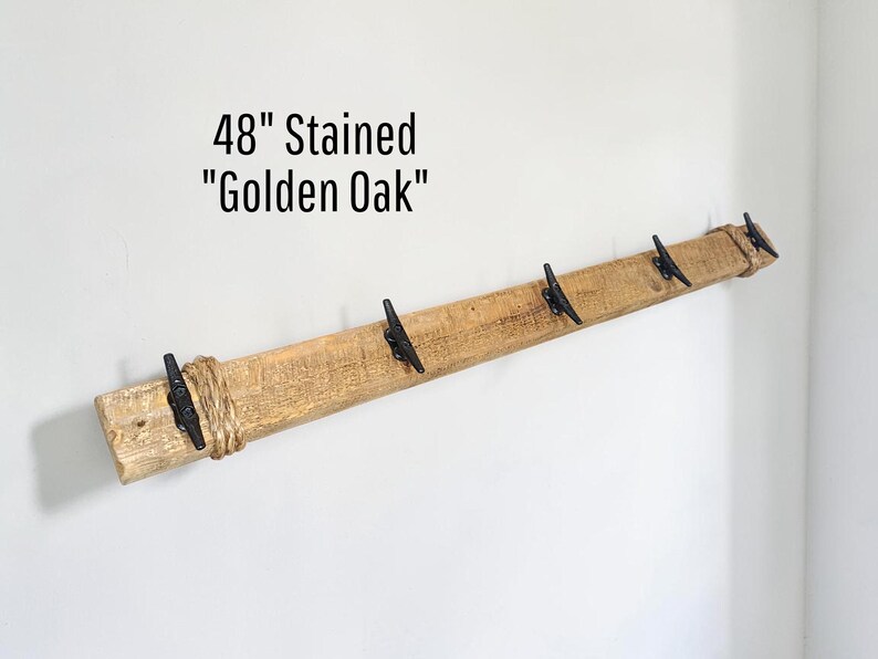 Solid wood nautical theme style look wall mounted coat or towel rack for the bathroom or entryway. This coastal themed towel hooh has rust proof black cast iron boat dock cleats or deck hooks. the wood is distressed and aged with the look of driftwood or reclaimed wood.
