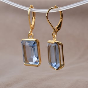 Puede incluir: Un par de pendientes de oro con gotas de piedras preciosas azul claro. Los pendientes tienen un cierre de palanca.