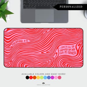 May include: A personalized desk mat with a red and pink wavy pattern. The mat features the text "Philippians 4:13" and "I can do all this through him who gives me strength". Available in multiple colors.