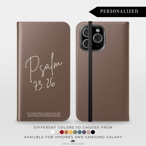 May include: A brown leather phone case with the text "Psalm 73:26" in a handwritten style. The case is shown open and closed, with a black elastic band. The text "MY FLESH AND MY HEART MAY FAIL..." is also visible. The word "PERSONALIZED" is at the top.