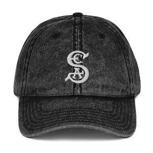 May include: A black vintage washed denim baseball cap with a white embroidered letter 'S' on the front.
