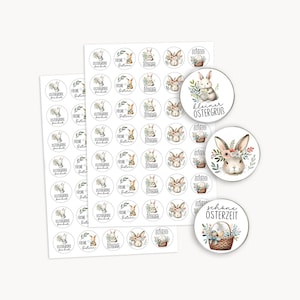 Op de afbeelding: Vellen ronde stickers met illustraties van paashazen en bloemaccenten. De stickers bevatten zinnen als "Frohe Ostern" en "kleiner Ostergrub". De ontwerpen zijn in zachte pastelkleuren.