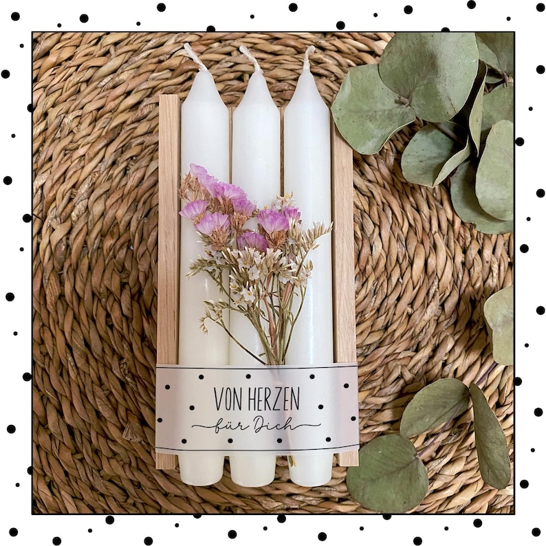 May include: Three white candles in a wooden box with a label that says "Von Herzen f&uuml;r Dich". The candles are surrounded by dried flowers.