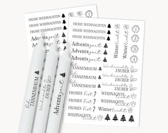 May include: Three white taper candles featuring black printed German holiday text and icons, alongside two sheets of matching black and white adhesive decals with phrases like Frohe Weihnachten, Adventszeit, and Oh Tannenbaum with festive graphics.