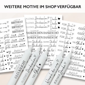 May include: A set of six white candles with black text and hearts. The candles have different phrases printed on them, including "Happy Birthday", "Viel Gl&uuml;ck", "Kleines Gl&uuml;ckslicht", "Wunsch dir was", "Ich sage Danke", and "Dankesch&ouml;n".