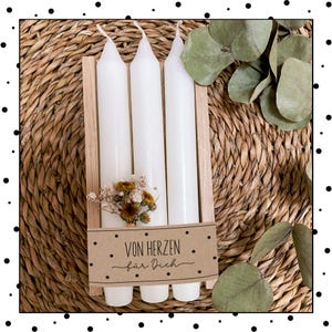 May include: Three white candles in a wooden holder with a brown paper tag that says "Von Herzen f&uuml;r Dich".