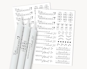 Op de afbeelding: Drie witte kaarsen met feestelijke Duitse opschriften en stickervellen met kerstthema woorden en afbeeldingen. De stickers bevatten zinnen als "Frohe Weihnachten" en afbeeldingen van sterren en cadeaus.