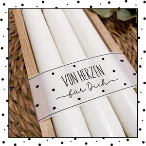 May include: Three white candles in a wooden box with a white label that says "Von Herzen f&uuml;r Dich".