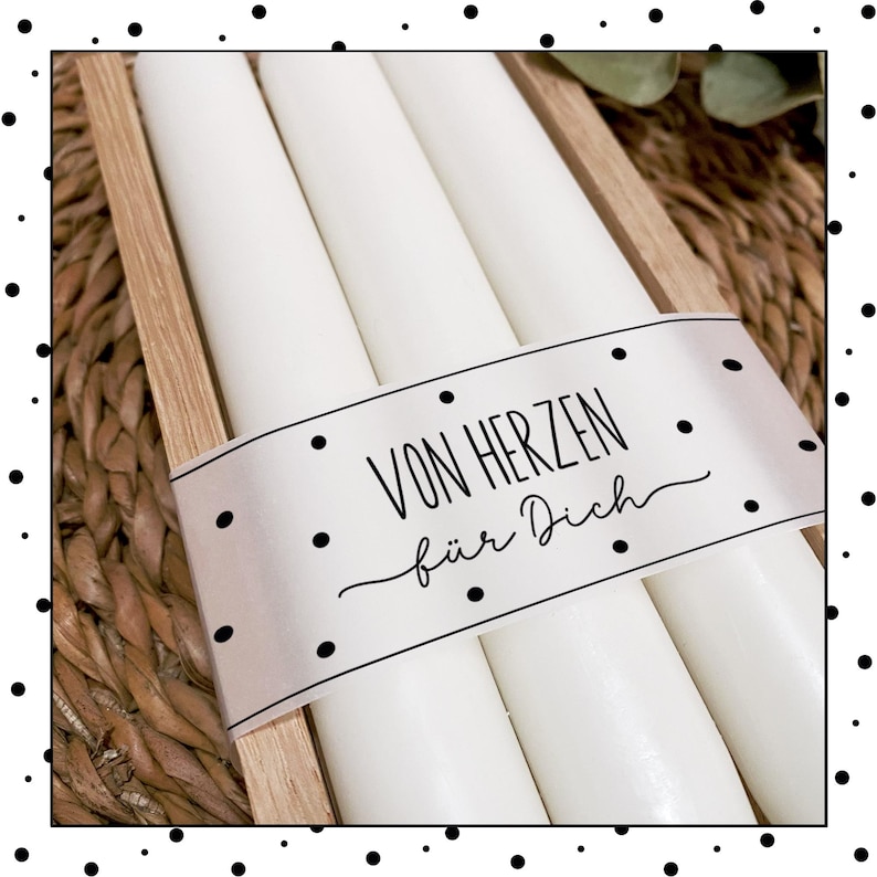 May include: Three white candles in a wooden box with a white label that says "Von Herzen f&uuml;r Dich".