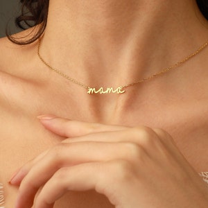 May include: A gold-toned necklace featuring a delicate chain and a central pendant in a cursive script font that spells out the word mama. The metal has a polished finish, and the pendant is integrated directly into the thin, lightweight chain design.