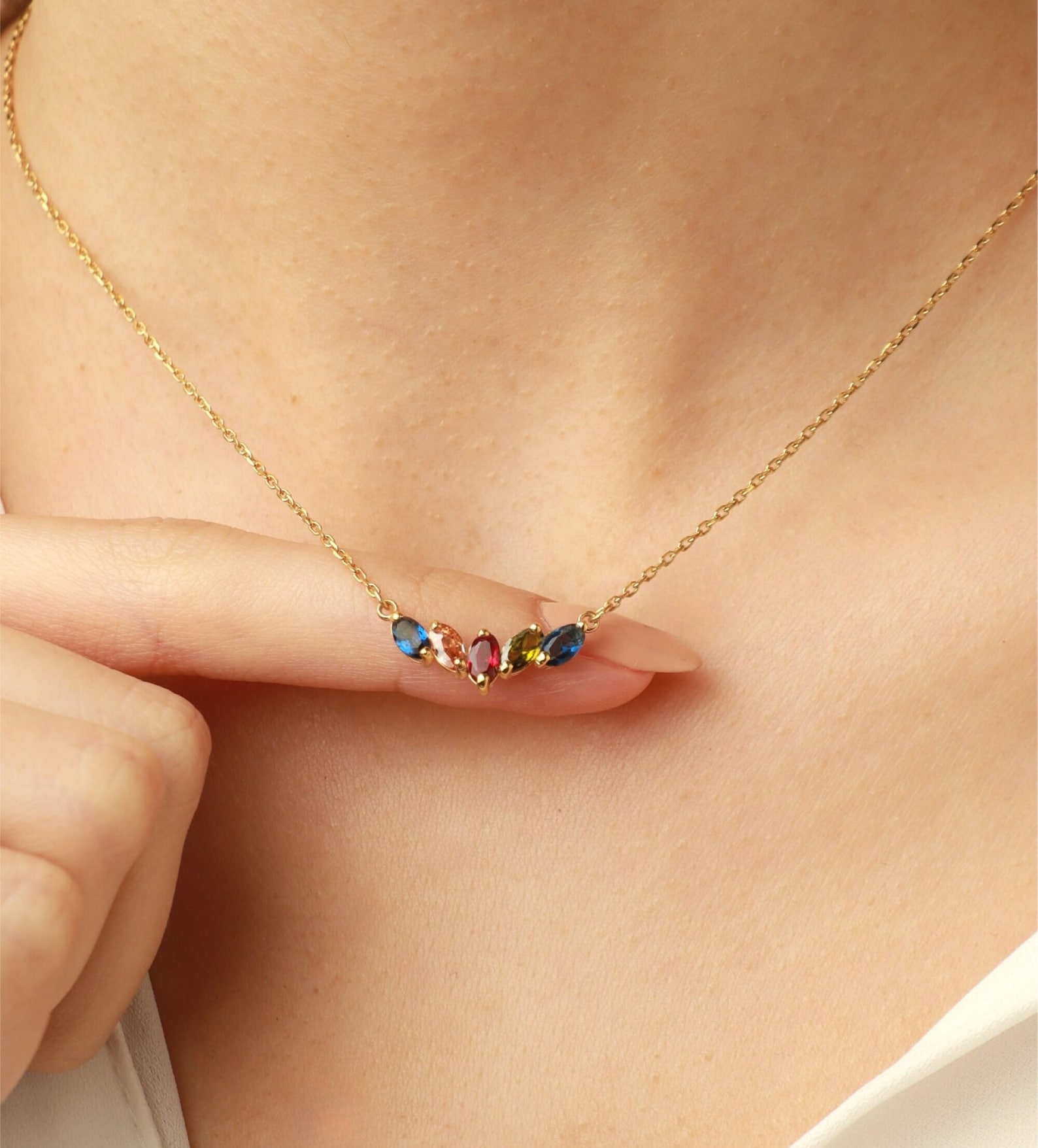A birthstone necklace with 5 colored stones on a gold plated chain