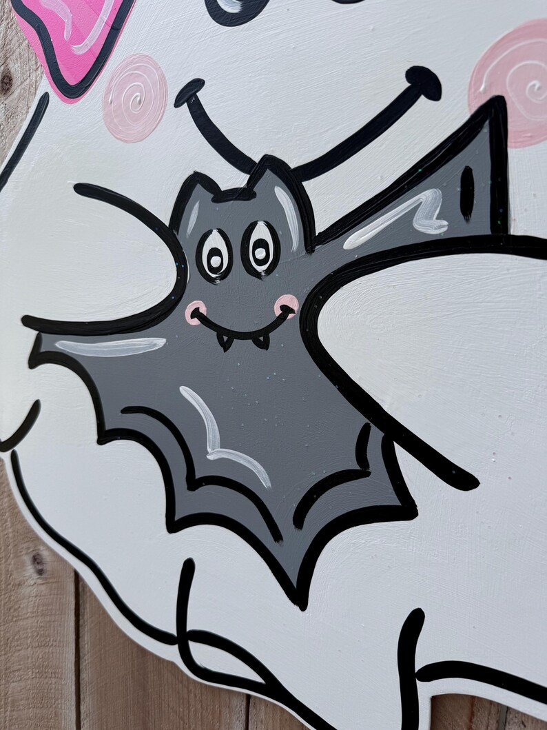 May include: A white ghost with a pink bow and a black outline holds a gray bat with white eyes and a black mouth. The bat has a pink blush on its cheeks.