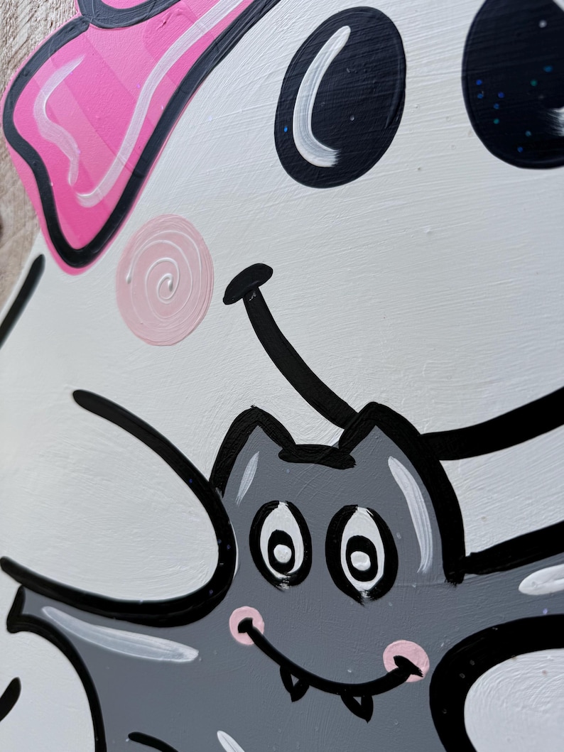 May include: A white ghost with a pink bow and black eyes is holding a gray bat with black eyes and a pink mouth. The bat has white teeth and is smiling.