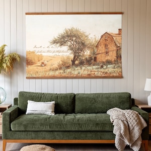 May include: A green velvet sofa with a throw blanket and a woven footstool in front of a wall with a framed print that reads "Dwell in the land of the living, I seek His faithfulness, Psalm 91:2".