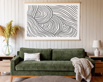 May include: A living room scene featuring a green velvet sofa, a round wooden coffee table, and a large abstract art print with black lines on a white background. A beige throw blanket and a white pillow with black stripes add texture.