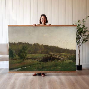 Peut inclure: Une grande peinture de paysage représentant un pont en bois sur un ruisseau, avec des champs verts et des arbres sous un ciel nuageux. L'œuvre est encadrée dans un cadre en bois et comprend du texte manuscrit. Le thème est la nature et le paysage.