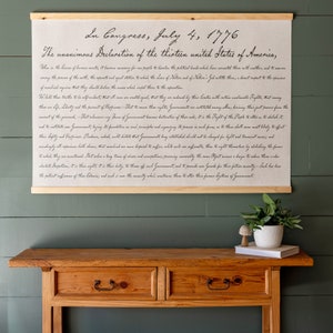 K&ouml;nnte beinhalten: Ein gerahmter Druck der Unabh&auml;ngigkeitserkl&auml;rung, in Kursivschrift auf beigefarbenem Hintergrund geschrieben. Der Text lautet "In Congress, July 4, 1776 The unanimous Declaration of the thirteen united States of America."