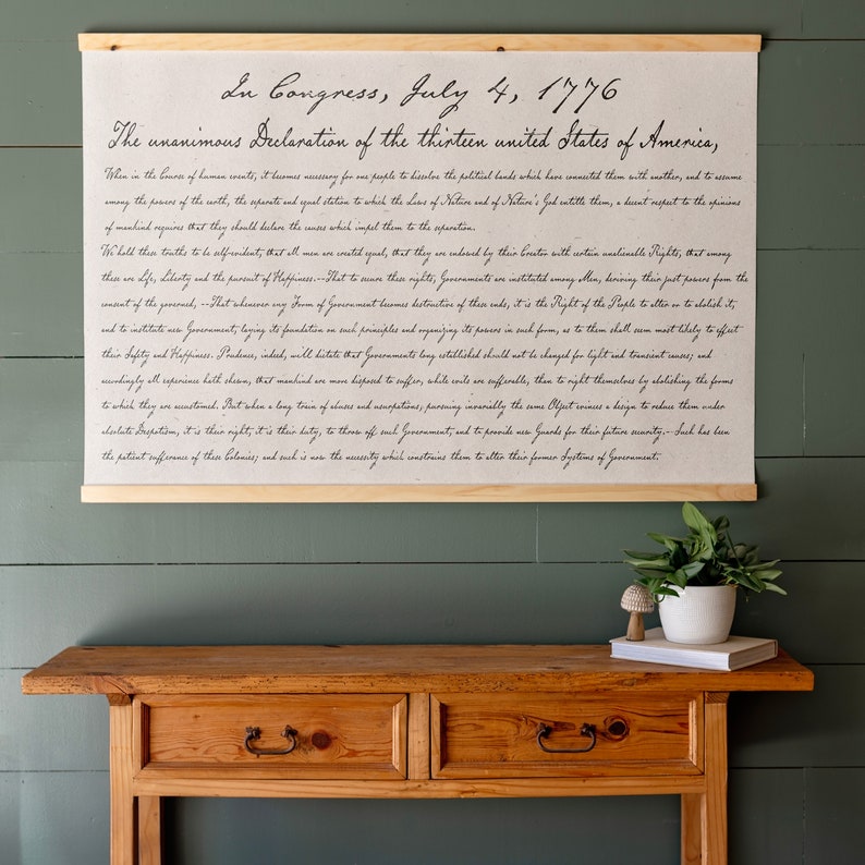 K&ouml;nnte beinhalten: Ein gerahmter Druck der Unabh&auml;ngigkeitserkl&auml;rung, in Kursivschrift auf beigefarbenem Hintergrund geschrieben. Der Text lautet "In Congress, July 4, 1776 The unanimous Declaration of the thirteen united States of America."