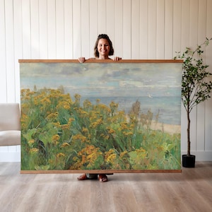 May include: A painting of a seascape with yellow wildflowers in the foreground. The painting is framed in a wooden frame.