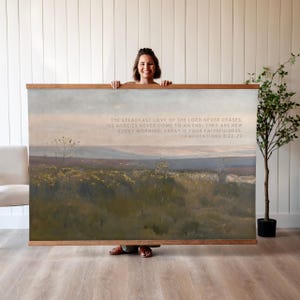 May include: A landscape print with a wooden frame, depicting a field of yellow flowers and text from Lamentations 3:22-23. The artwork uses a muted palette of greens, blues, and browns, creating a calm and natural aesthetic.
