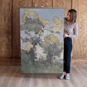 May include: A watercolour painting of a landscape with trees and a body of water in the distance. The painting is framed in a wooden frame.