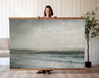 May include: A framed seascape painting depicting a stormy ocean with waves crashing on the shore. The sky is a muted gray with hints of blue, and the water is a deep green and white.