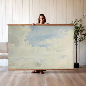 May include: A large rectangular wall art print depicting a tranquil sky with white clouds and a light blue background. The print is framed with a natural wood border and includes the text "Your love, Lord, reaches to the heavens, your faithfulness to the skies."
