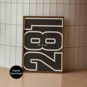 May include: A framed art print featuring the number "281" in a bold, white font against a black background. The word "HOU" is centered within the "8". The print is in a brown frame and the words "Digital Download" are on a black circle in the lower left corner.