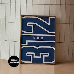 Puede incluir: Una impresión artística enmarcada con el número "312" en blanco sobre un fondo azul marino, con "CHI" debajo. El marco es de color marrón oscuro. Las palabras "Digital Download" están en un círculo negro en la esquina inferior izquierda. La impresión está contra una pared de azulejos blancos.