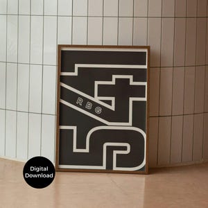 Puede incluir: Un póster enmarcado en blanco y negro con las letras y números "175" en un diseño geométrico audaz. Las letras "RBG" están impresas en diagonal. El póster está en un marco marrón.