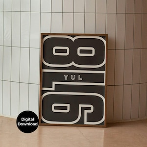 Könnte beinhalten: Ein gerahmter Kunstdruck mit der Zahl "816" in großen weißen Blockbuchstaben auf schwarzem Hintergrund. Das Wort "TUL" ist unter den Zahlen zentriert. Der Rahmen ist dunkelbraun, und ein "Digitaler Download"-Aufkleber befindet sich unten links.