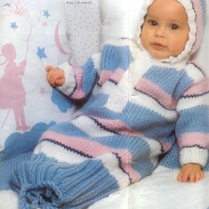 May include: A baby wearing a knitted blue, white, and pink striped outfit with a matching hood. The outfit appears to be a one-piece design, possibly a sleep sack or bunting bag. The image includes the text "Explained from 3-6 months."