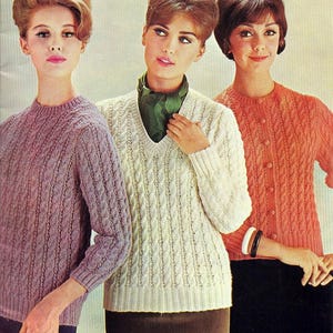 Puede incluir: Fotografía vintage de tres mujeres con suéteres de punto trenzado. Los suéteres son en tonos lavanda, crema y coral. Las mujeres tienen peinados abombados y faldas oscuras. La imagen tiene una estética retro.