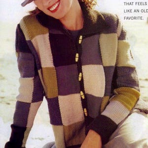 May include: A woman wearing a patchwork cardigan with wooden buttons and a matching hat. The sweater features a checkerboard pattern in shades of gray, beige, and olive green. The text in the image reads: "KICK BACK AND RELAX IN A NEW SWEATER THAT FEELS LIKE AN OLD FAVORITE."